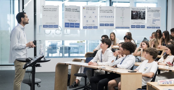 A teacher is giving a presentation to a classroom of students who are attentively listening.