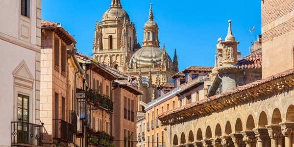 A picturesque view of historic buildings and cathedral domes under a clear blue sky.