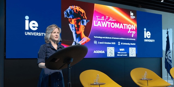 A speaker presenting at the Lawtomation event held at IE University, featuring a colorful backdrop.