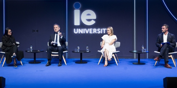 Four professionals are seated on stage at a panel discussion at IE University.
