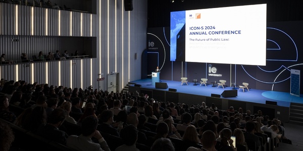 An audience attentively listens at the ICONS 2024 Annual Conference on the future of public law, held in a modern auditorium.