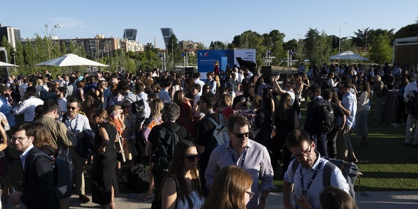 A large group of people gathered outdoors at a social event, possibly a festival or conference, with some wearing business attire.