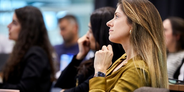 A woman thoughtfully listening in a classroom setting.