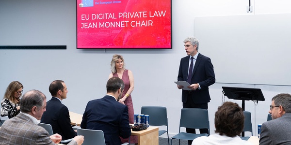 A conference or seminar focused on EU digital private law is taking place with a speaker at the front.