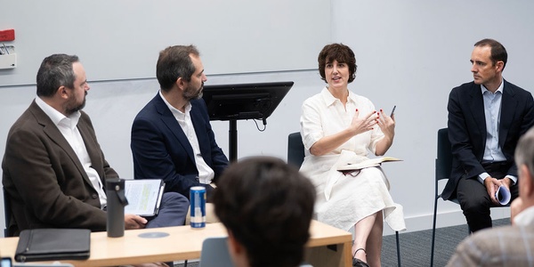 A panel discussion featuring four speakers seated at a table.