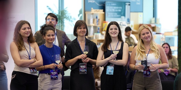 A group of people at an event, smiling and holding drinks.