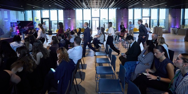 A group of people seated in a modern, spacious venue preparing for an event.