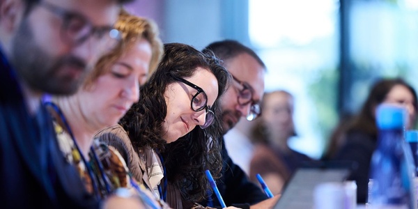 A group of people focusing on a meeting or workshop while taking notes.