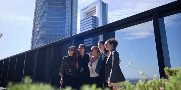 A group of women posing for a photo in front of modern buildings.