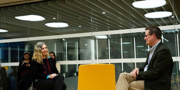 A man and a woman sitting in a modern office space, talking.