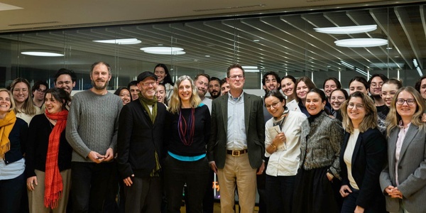 A group of approximately twenty people posing for a photo in a modern office setting.