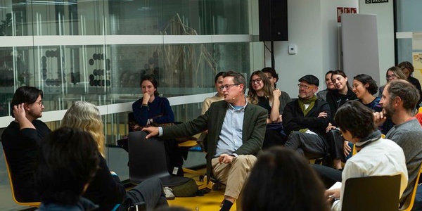 A group of people sitting in a semi-circle in a modern office environment, engaging in a discussion.