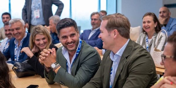 A group of people in a meeting room engaged in conversation and smiling.