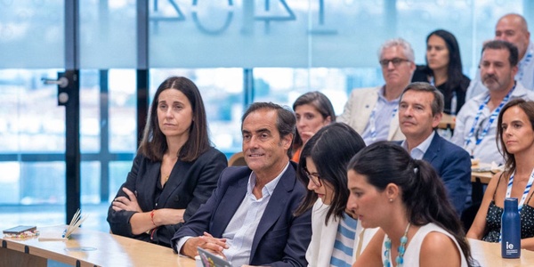 A diverse group of people sitting attentively in a modern conference setting.