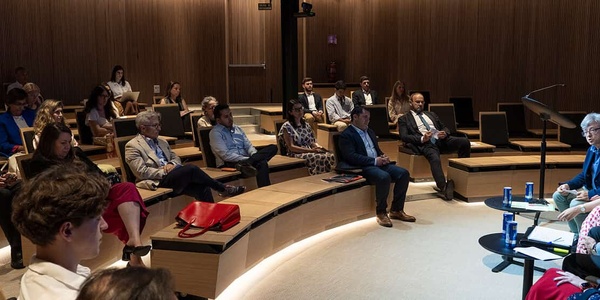 A panel discussion taking place in a modern auditorium with an audience.