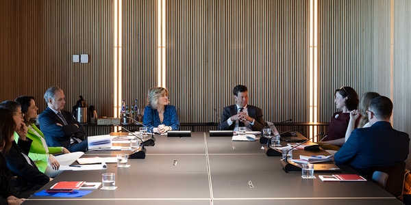 A group of people sitting around a conference table in a modern meeting room.