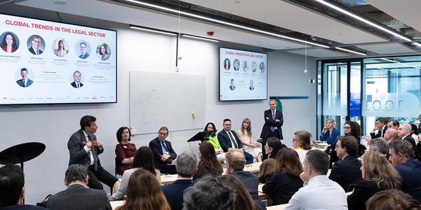A conference scene with a speaker presenting on global trends in the legal sector to an attentive audience.