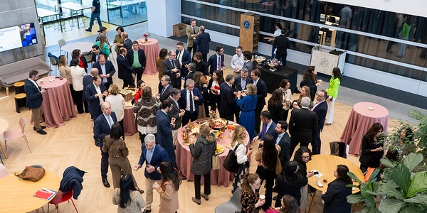 A large group of people mingling at a social event in a modern indoor space.