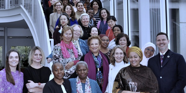 A diverse group of women posing together on a staircase in a modern building.