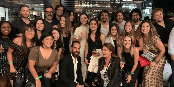 A group of people posing for a photo at a night event, smiling and holding drinks.