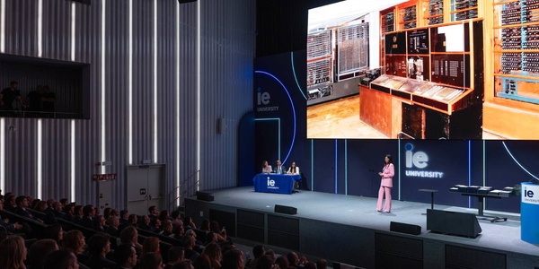A presentation at a university featuring a historic computing machine displayed on a large screen.