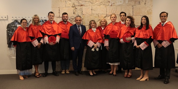 A group of people dressed in formal academic regalia standing in a room.