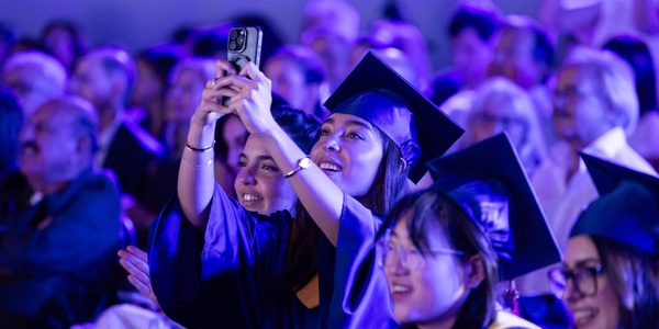 A group of graduates celebrating during a ceremony with joyful expressions.