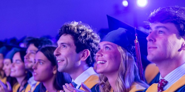 A group of graduates celebrating at a ceremony with smiles and excitement.