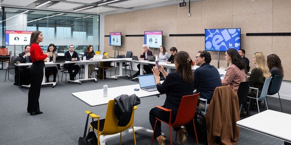 A group of professionals in a meeting room engaging in a discussion with a speaker.