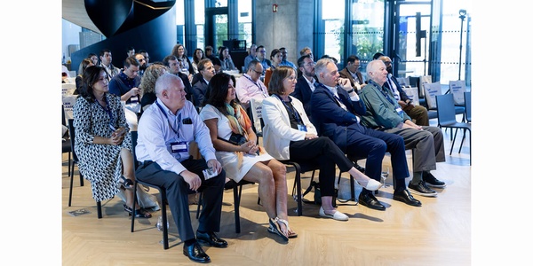 A diverse audience is attentively listening to a presentation in a modern venue.