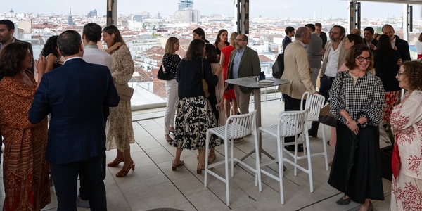 A gathering of people socializing at a rooftop venue with a city view.