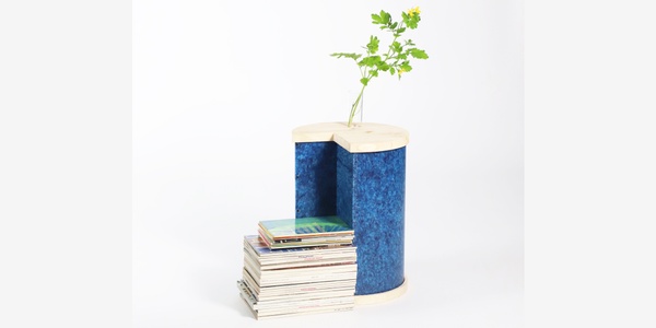 A small plant growing out of a cylindrical container placed on a pile of books against a white background.