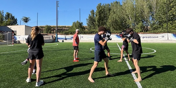 A group of people practicing boxing on a grassy field.