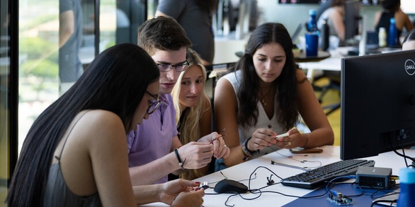 A group of students collaborating on a project at a computer workstation.