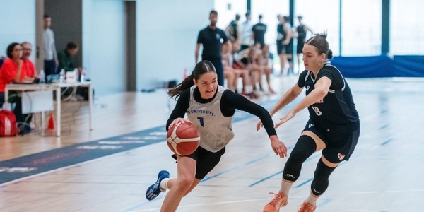 Two female basketball players are competing in a game.