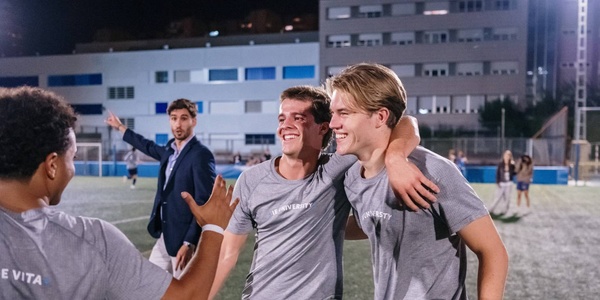A group of young men celebrating on a sports field at night.