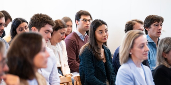 A group of people sitting in a row, attentively listening in a seminar or class.