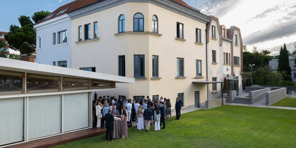A group of people gathered outside a modern house for an event.