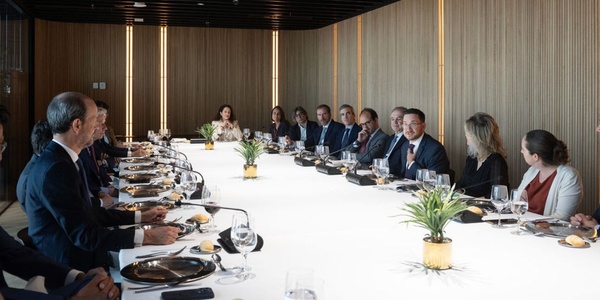 A group of professionals gathered around a long dining table in a modern meeting room.