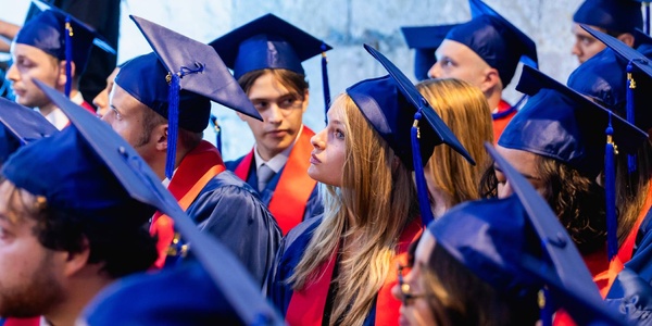 A group of graduates wearing caps and gowns during a ceremony.