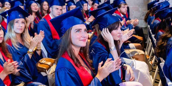 A group of graduates in blue caps and gowns celebrating during a ceremony.