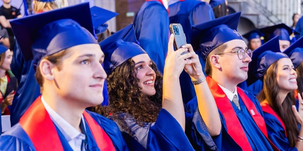 A group of graduates in caps and gowns celebrating at a graduation ceremony.