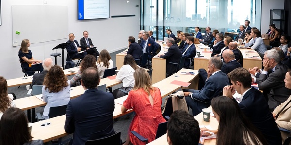 A diverse group of professionals are attending a seminar in a modern conference room.