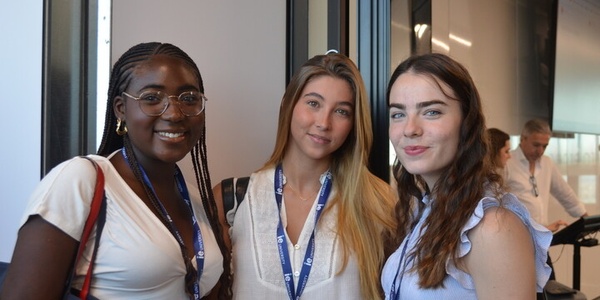 Three young women smiling together at an event.