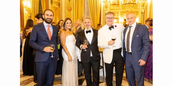 A group of five elegantly dressed people posing together at a formal event.