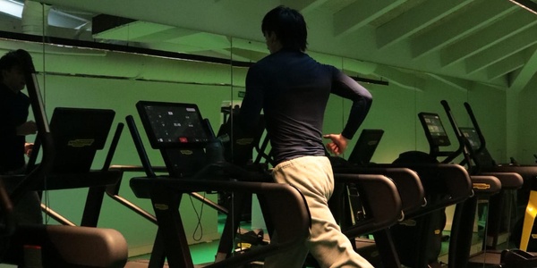 A person running on a treadmill in a gym setting.