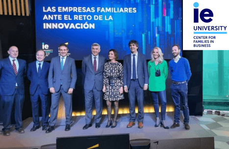 A group of eight professionals standing on stage at an IE University event focused on family businesses and innovation.