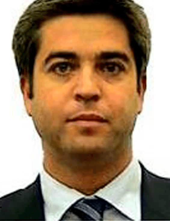 Portrait of a man with dark hair wearing a suit and tie, facing forward.