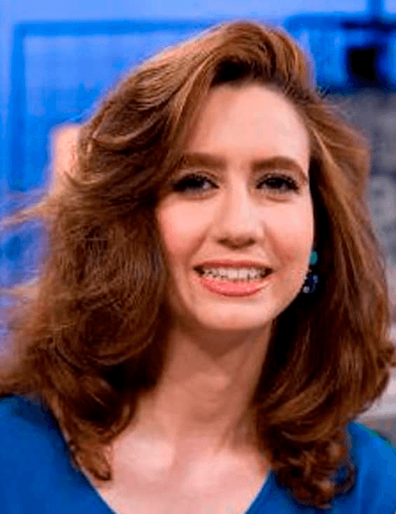 A smiling woman with shoulder-length brown hair wearing a blue top.