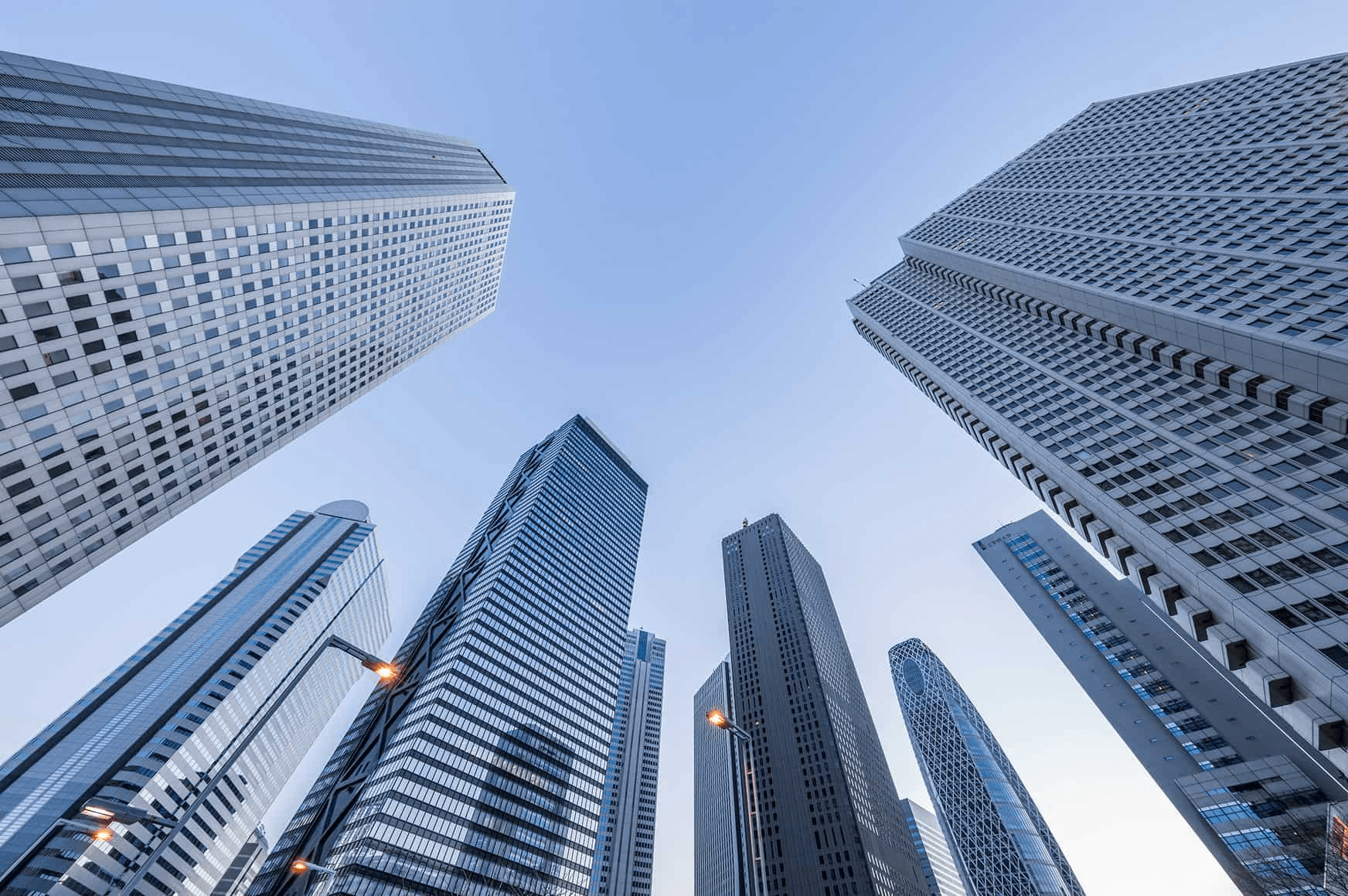 A view looking up at tall skyscrapers against a clear sky.
